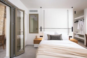 Un dormitorio moderno con una cama grande, una puerta corrediza de vidrio, un armario empotrado y una zona de estar con una silla.