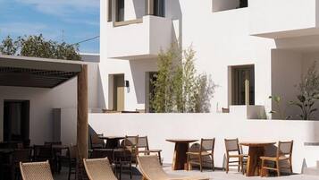 Un edificio moderno con zona de piscina, mobiliario exterior y cielo despejado.