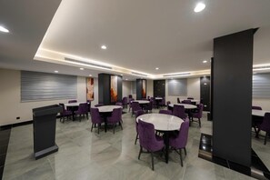 A modern dining area with round tables and purple chairs, featuring a central column and artwork on the walls. - Gardn Millennium Al-salamah Hotel Jeddah (Jeddah)