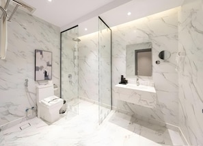 A modern bathroom with a glass-enclosed shower, a toilet, a sink with a mirror, and marble walls. - Gardn Millennium Al-salamah Hotel Jeddah (Jeddah)