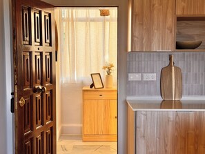 A wooden door with a brass handle, a wooden cabinet with a vase of flowers, and a wooden cutting board on a countertop. - Beachfront • Sea Views • The Mimosas • La Cala de Mijas (La Cala de Mijas)