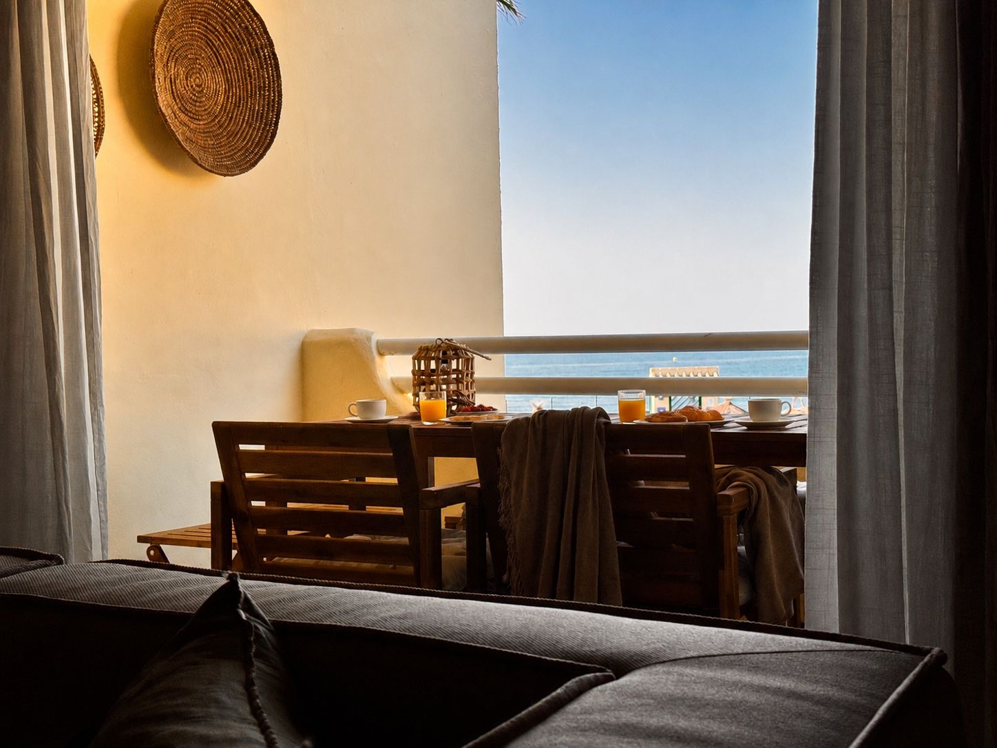 Un balcón con una mesa dispuesta para el desayuno, con vista a un cuerpo de agua.