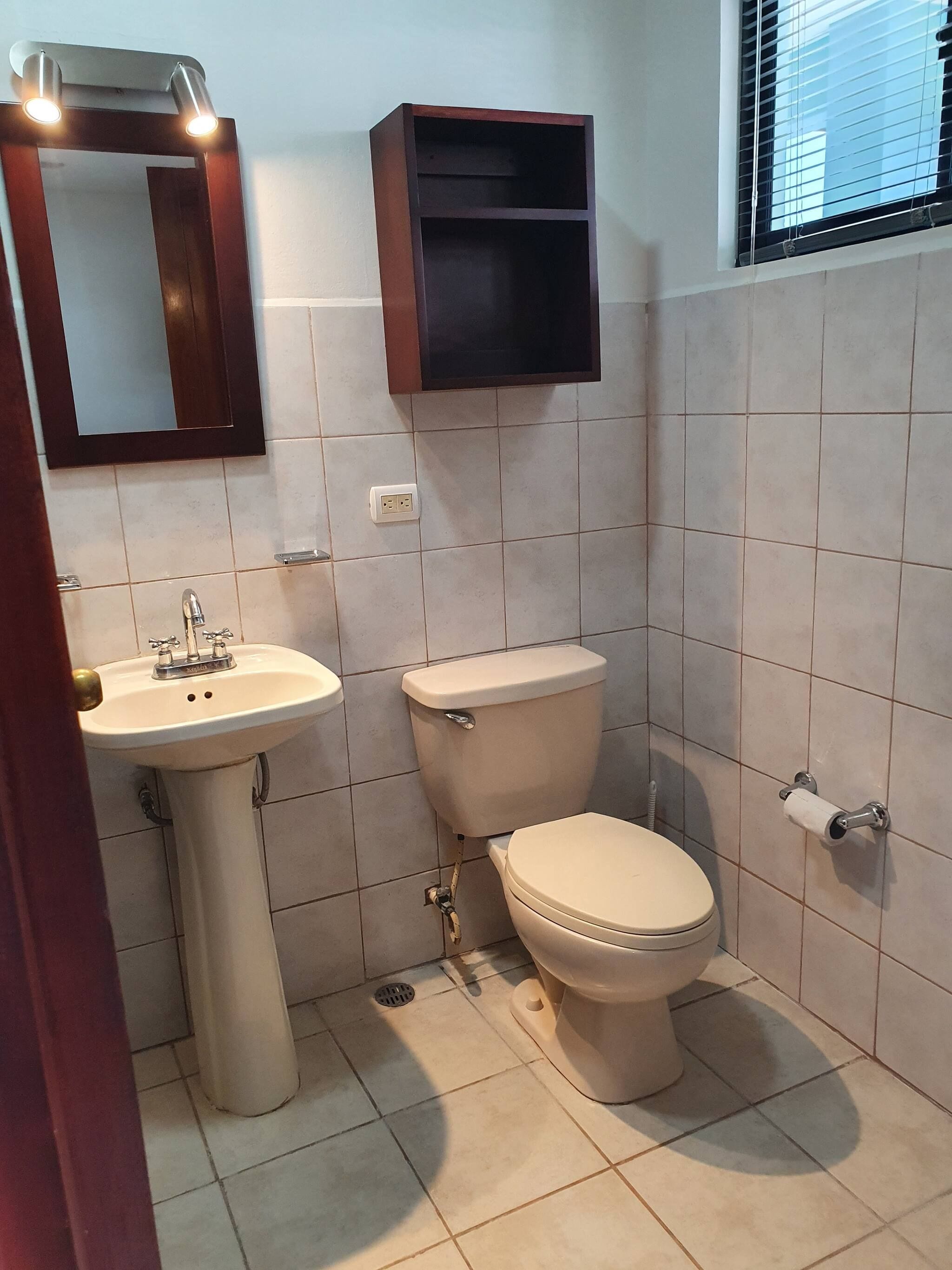 Un baño con lavabo, inodoro y espejo.