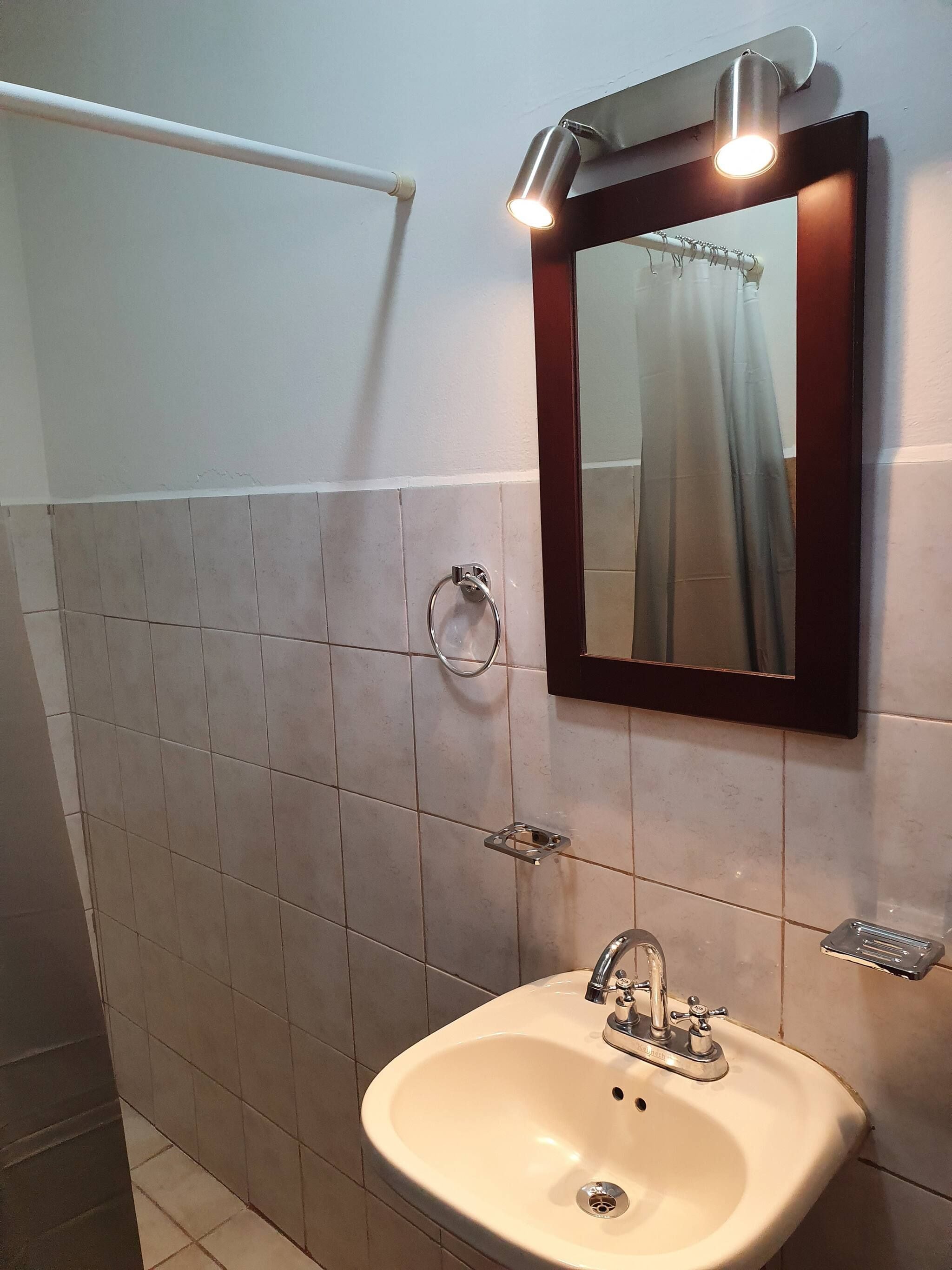 A bathroom with a sink, mirror, and towel rack.