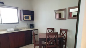 Een kleine keuken met een magnetron, een koffiezetapparaat en een eettafel met vier stoelen.
