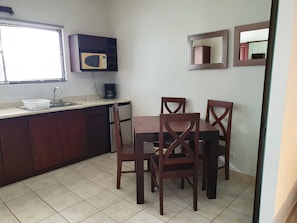 A compact kitchen with a microwave, a coffee maker, and a dining table with four chairs. - Marina Loft Studio # 207 (Sardinal)