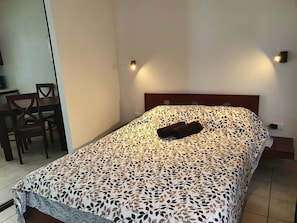 A neatly made bed with a leaf-patterned bedspread, a dark brown pillow, and two wall-mounted lights. - Marina Loft Studio # 207 (Sardinal)