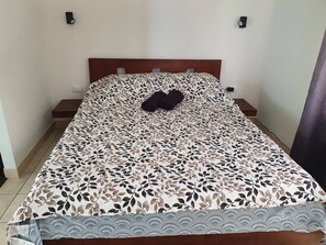 A bed with a leaf-patterned bedspread, two bedside tables, and a nightstand. - Marina Loft Studio # 207 (Sardinal)