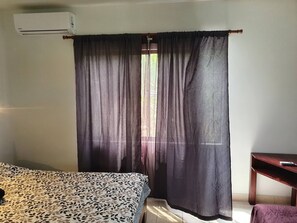 Une chambre avec un lit, un bureau et une fenêtre avec des rideaux.