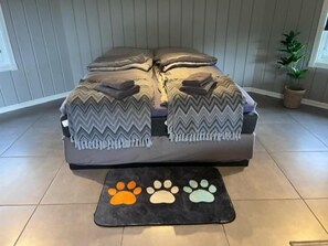 A bed with a chevron-patterned blanket, a pet bed with paw prints, and a potted plant to the side. - Blafjell Hundesenter Fjellhotell (Vefsn)