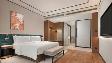 A modern hotel room with a large bed, bedside tables, a flat-screen TV, and a bathroom with a shower and toilet.