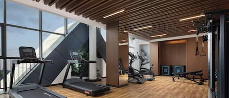 Un gimnasio con cintas de correr, elípticas y equipo de levantamiento de pesas.
