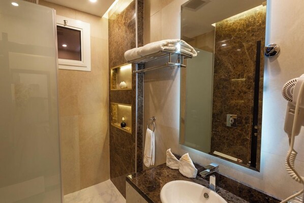 A modern bathroom with a glass shower enclosure, a marble countertop, a sink, and a mirror. - Aman Suites Hotel - Al Mhalh (Abha)