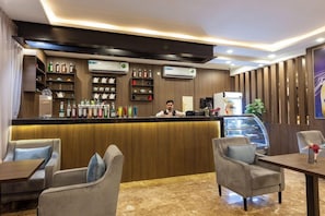 Un hall d’hôtel comprenant un comptoir d’accueil, un espace salon et une présentation de divers objets.