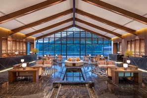 A spacious lobby with a high ceiling, a central seating area, and a large window offering a view of the outdoors. - Wyndham Qingyuan Lianzhou Hot Spring Resort (Qingyuan)