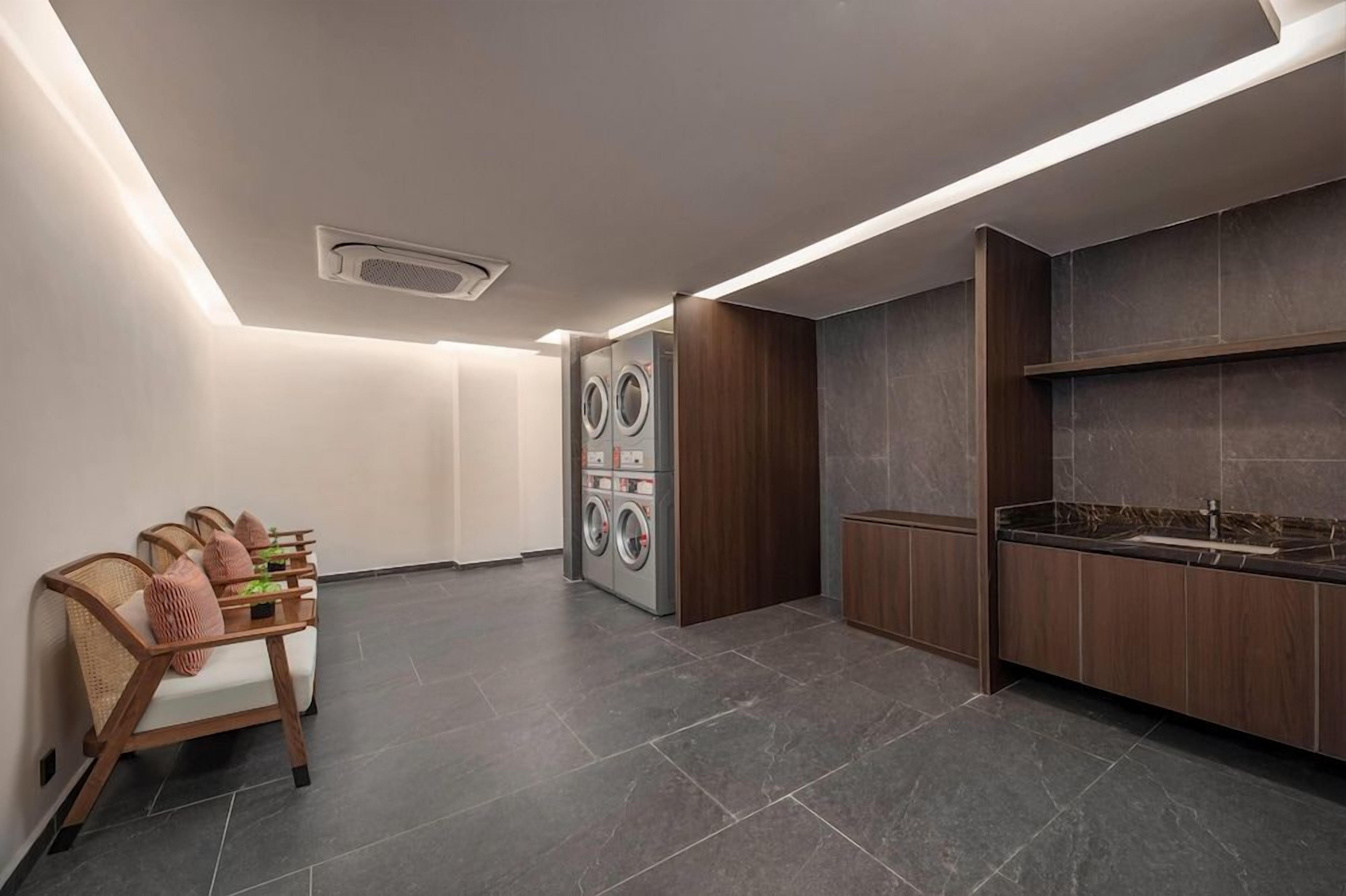 Un moderno lavadero con lavadora, secadora y una zona de estar con mesa y sillas.