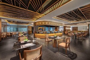 A modern restaurant with a central bar area, multiple dining tables, and a contemporary ceiling design. - Wyndham Qingyuan Lianzhou Hot Spring Resort (Qingyuan)
