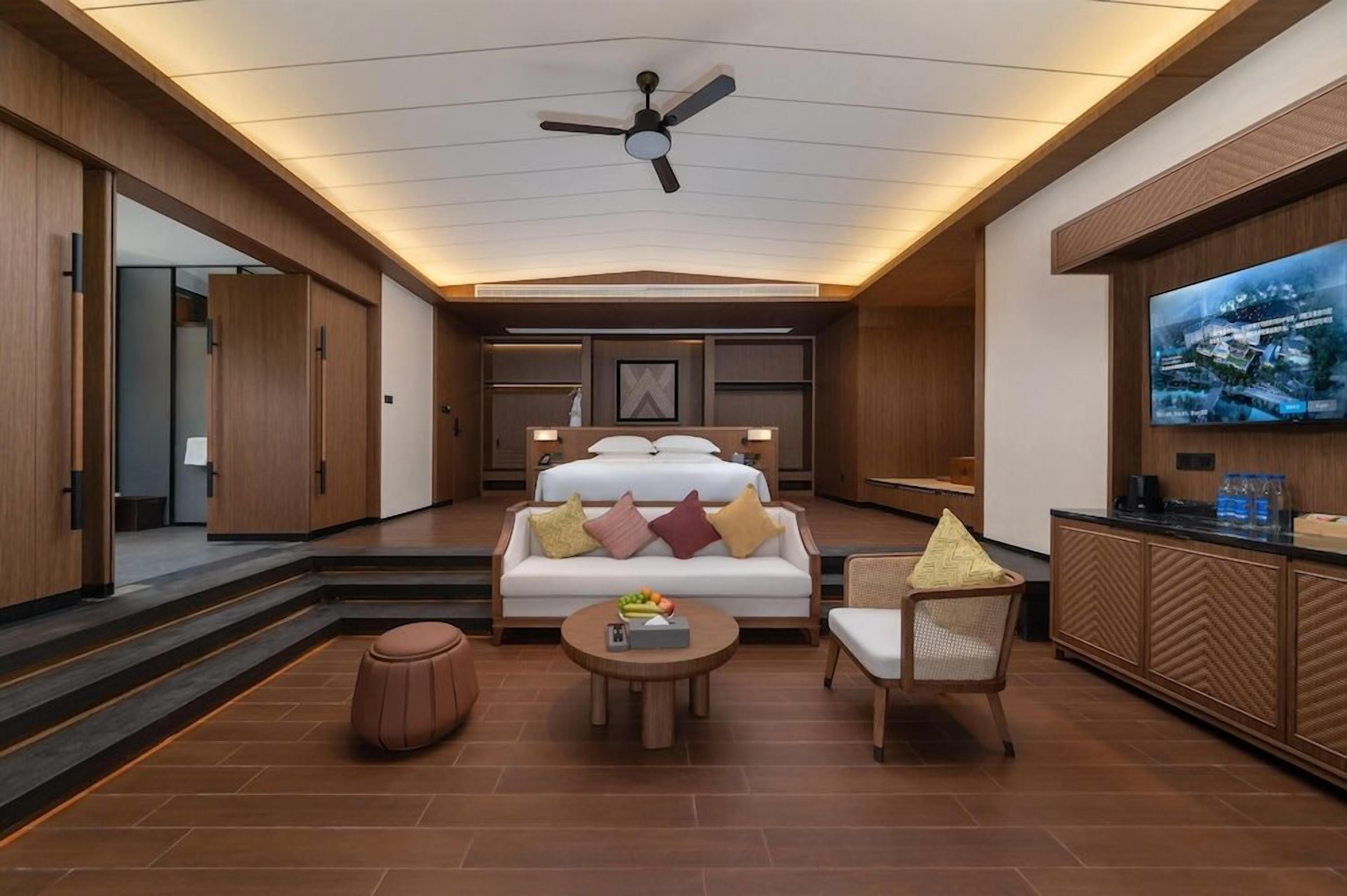 A hotel room with a bed, a sofa, a TV, and a coffee table.