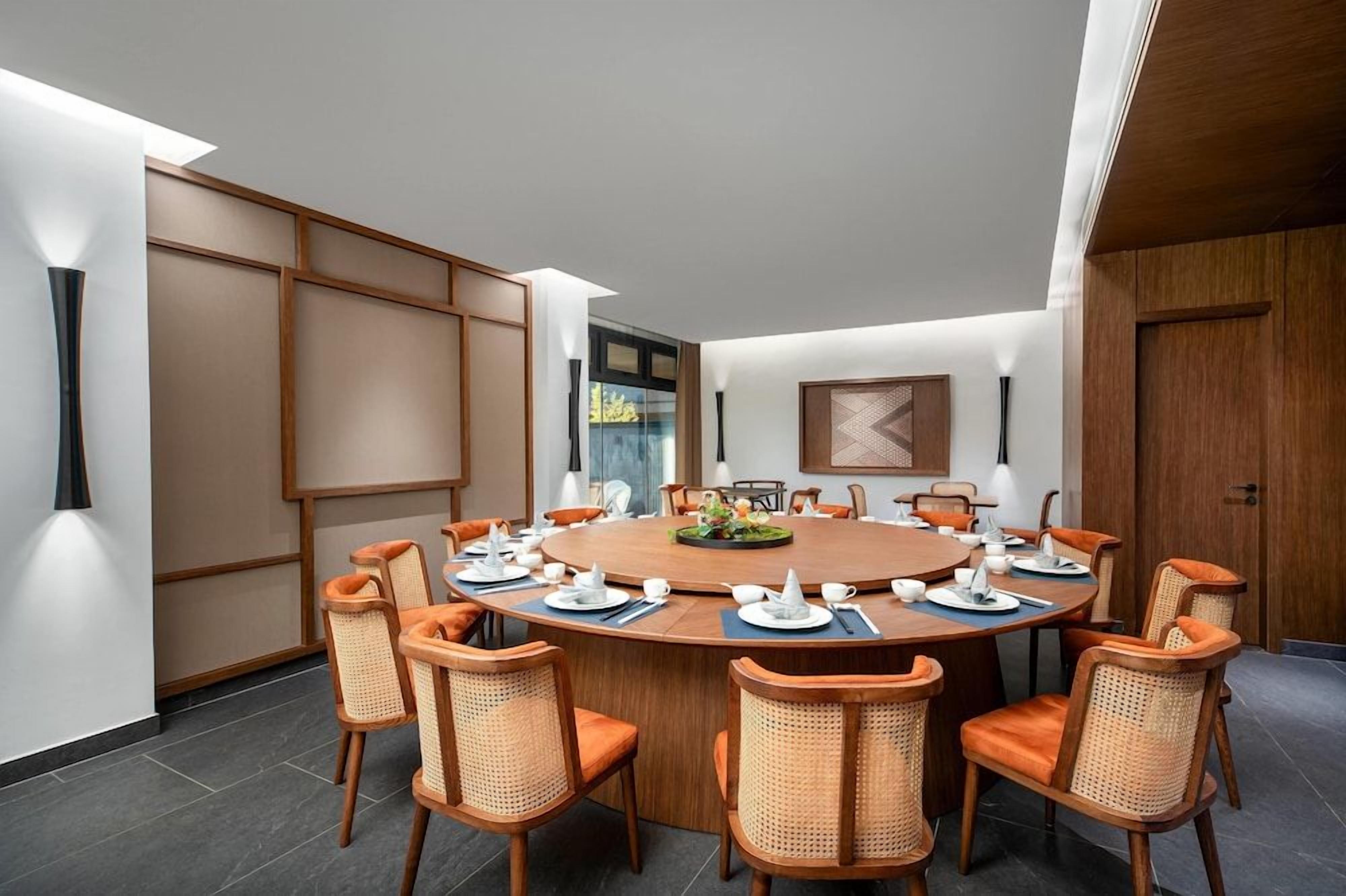 Un salón de conferencias con una mesa redonda, sillas naranjas y un diseño interior moderno.