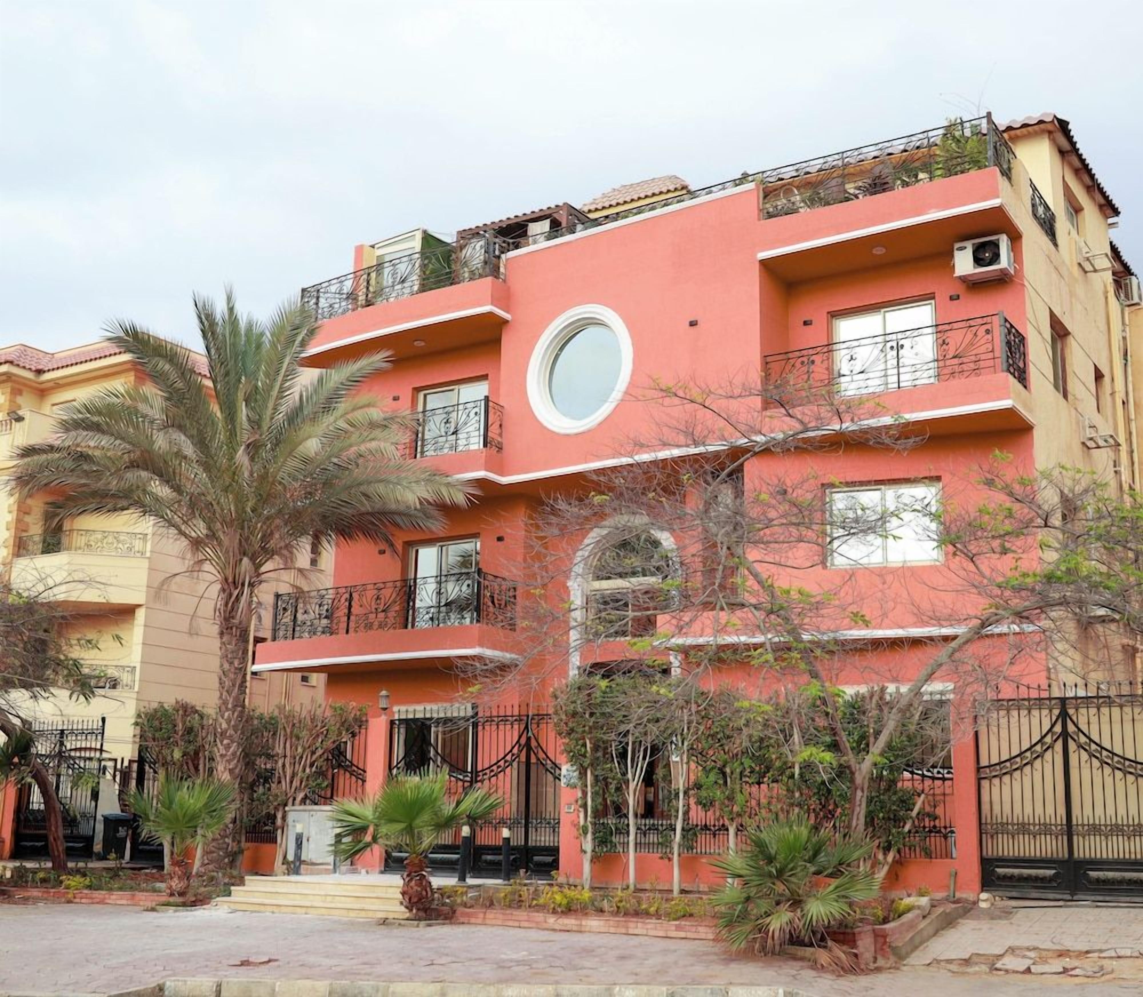 A multi-story building with balconies, a circular window, and a gated entrance.