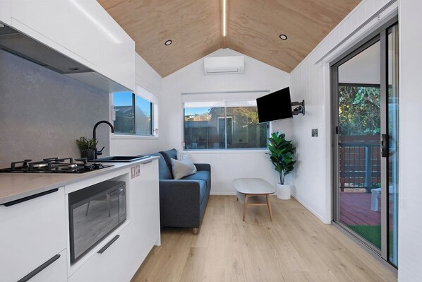 A compact kitchen with a microwave, stove, and a small dining area with a table and a sofa. - Reflections Holiday Parks Scotts Head (Scotts Head)