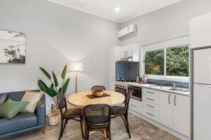 A compact kitchen with white cabinets, a round dining table, and a blue-tiled backsplash. - Reflections Holiday Parks Scotts Head (Scotts Head)