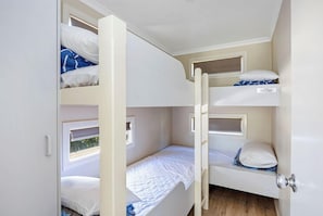A bunk bed room with a window, a door, and a small shelf. - Reflections Holiday Parks Scotts Head (Scotts Head)