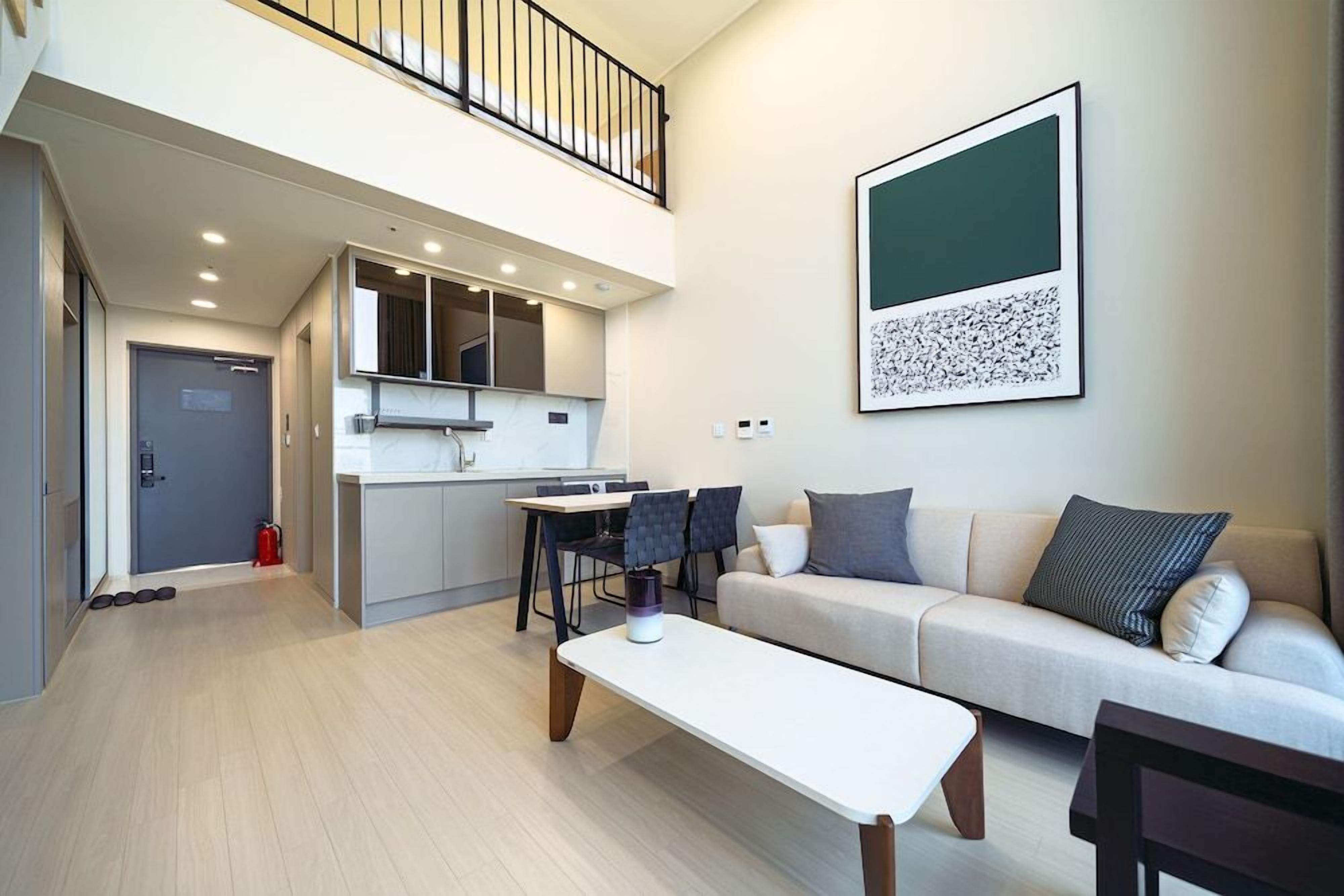 Un apartamento moderno con comedor, kitchenette y sala de estar con sofá y mesa de centro.