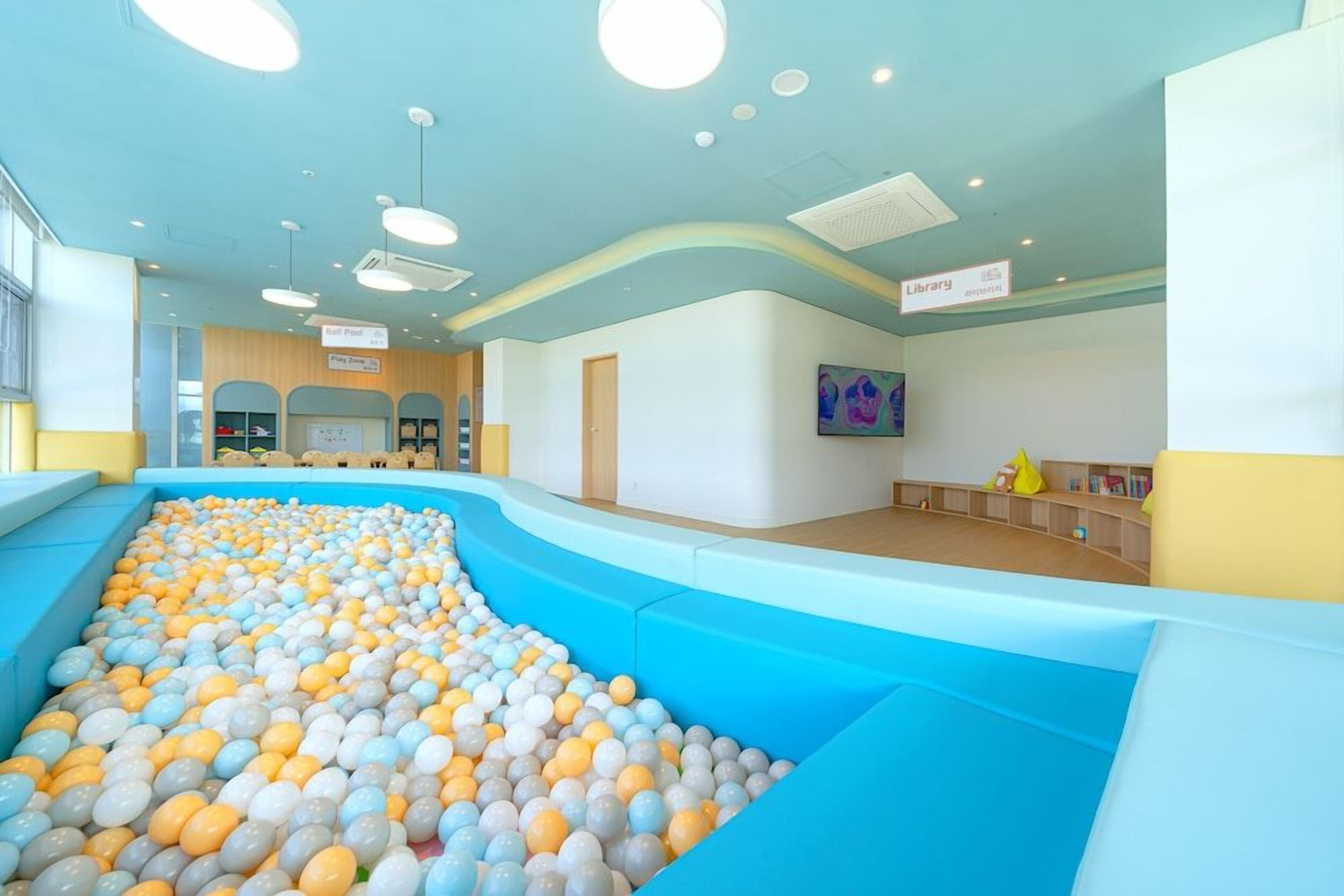 Un área de juegos infantiles con piscina de pelotas y una sección de biblioteca.