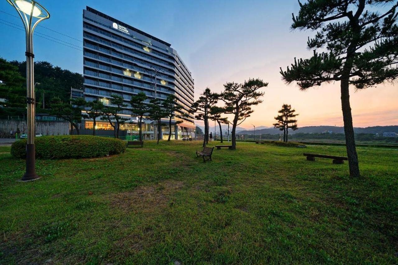 Un hotel con diseño moderno, un patio con césped y bancos, y vistas del paisaje circundante.