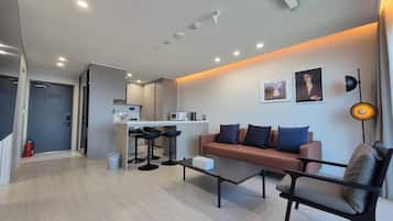 A modern living room with a sofa, a coffee table, and a dining area with a kitchen in the background.