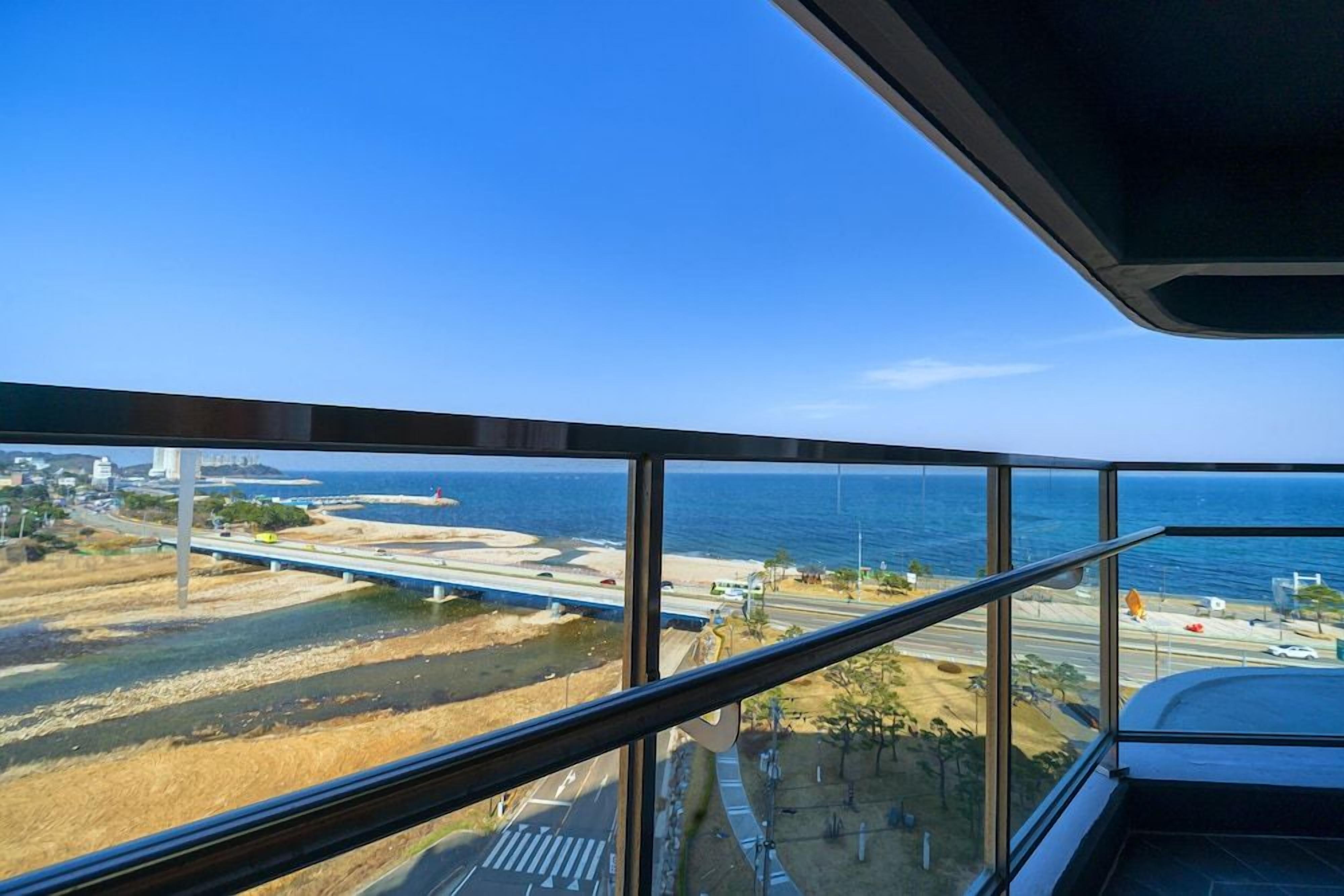 A view from a high-rise building overlooking a coastal area with a bridge, roads, and a beach.