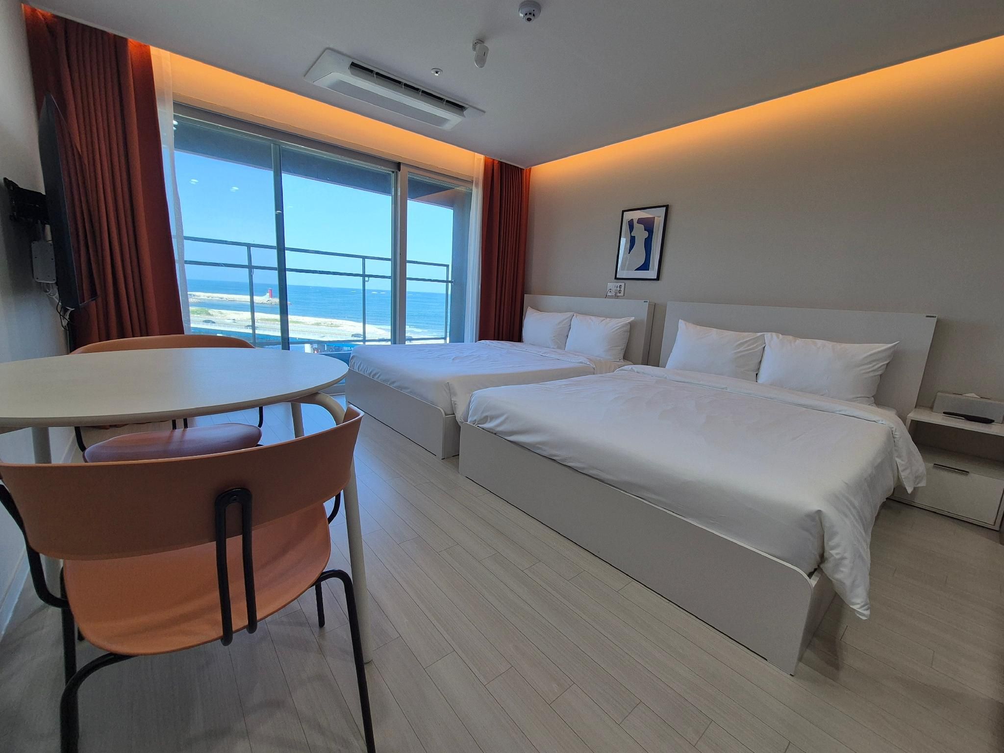 A hotel room with two beds, a dining table, and a chair.