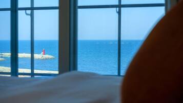 A window with a view of the sea and a lighthouse.