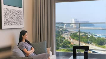 Una mujer sentada en un sofá con vista a un paisaje urbano a través de un ventanal grande.