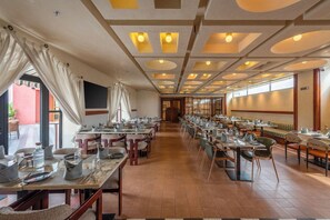 Un restaurant spacieux avec de nombreuses tables et chaises, un long comptoir et une vue sur l’extérieur.