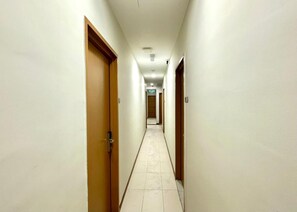 A long, narrow hotel corridor with doors on both sides and a tiled floor. - Swing & Pillows at Salak Tinggi Klia Transit (Sepang)