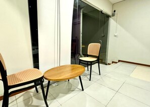 A room with two chairs and a small round table, a sliding glass door, and a tiled floor. - Swing & Pillows at Salak Tinggi Klia Transit (Sepang)