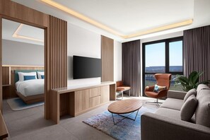 A modern hotel room with a bed, a TV, a desk, a sofa, and a large window with a view. - Courtyard by Marriott Dakar Diamniadio (Dakar)