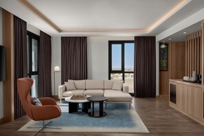 Uma sala de estar moderna com um sofá, uma poltrona, uma mesa de centro e uma vista através de grandes janelas.