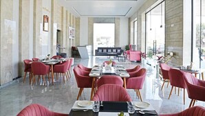 Un comedor moderno con sillas tapizadas en rojo, una mesa larga dispuesta para comer, y grandes ventanales que aportan luz natural.