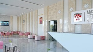 Un moderno vestíbulo de hotel con mostrador de recepción, zona de estar y una pantalla grande.