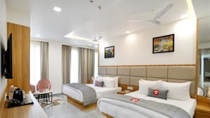 Habitación de hotel con dos camas, un escritorio, una silla, un televisor y un ventilador de techo.