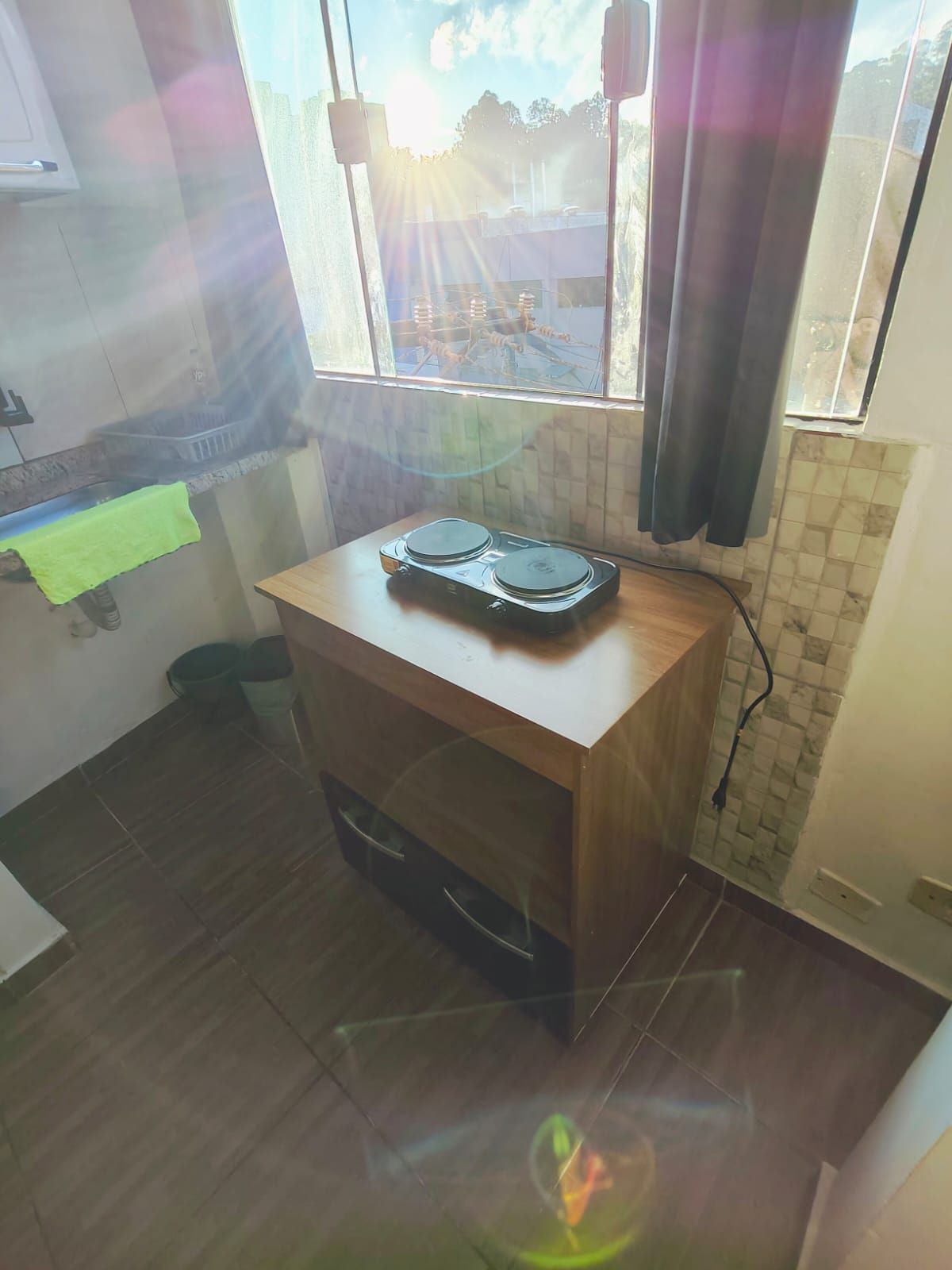 A small kitchen with a wooden countertop, a sink, and a window with a view of a parking lot.