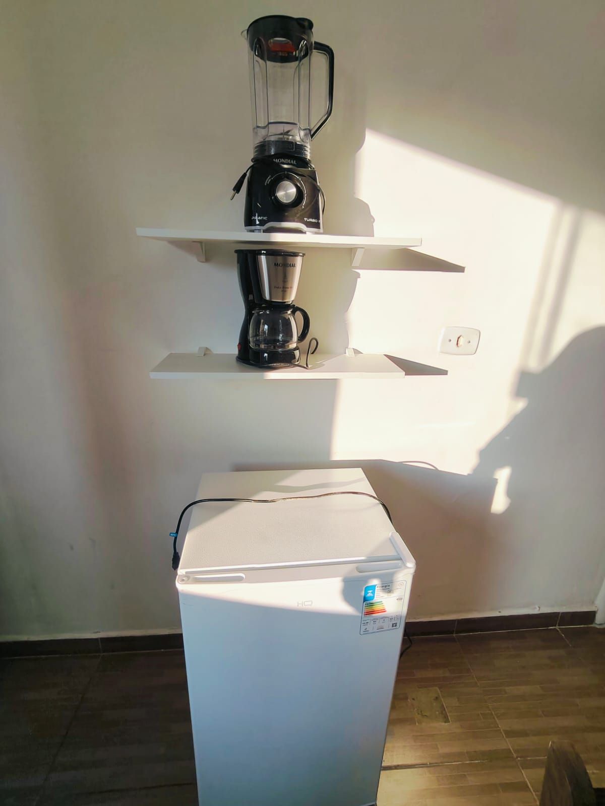 Een keuken met een blender op een plank, een koffiezetapparaat en een koelkast.