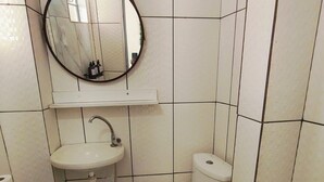 Kylpyhuone, jossa on wc, pesuallas ja peili.