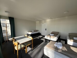 Une chambre d’hôtel avec un lit, un bureau, une chaise et une fenêtre avec des rideaux.