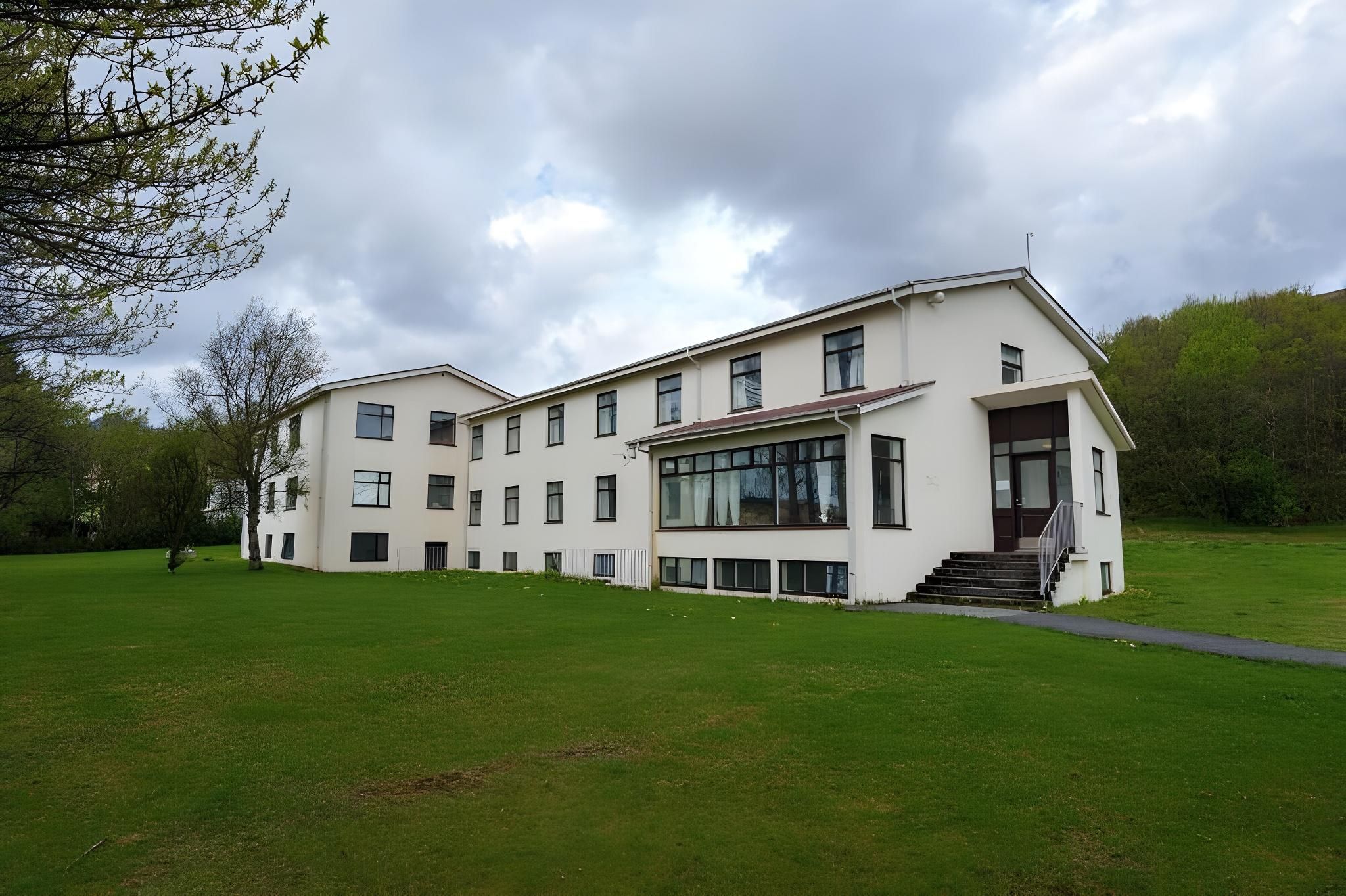 A two-story building with a flat roof, large windows, and a staircase leading to the entrance.