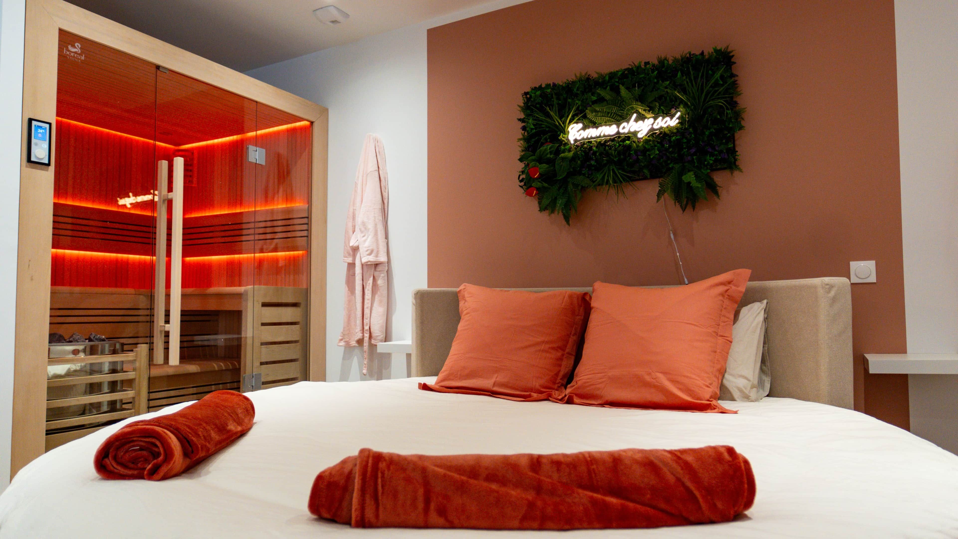 Une chambre d’hôtel avec un lit, une serviette rouge, un peignoir et un panneau fixé au mur.