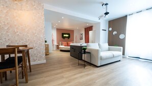 Een moderne woonkamer met een bank, een salontafel en een eethoek met een houten tafel en stoelen.
